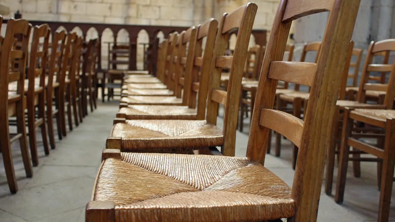 Rangée de chaises de bois à assise cannée dans une salle vide
